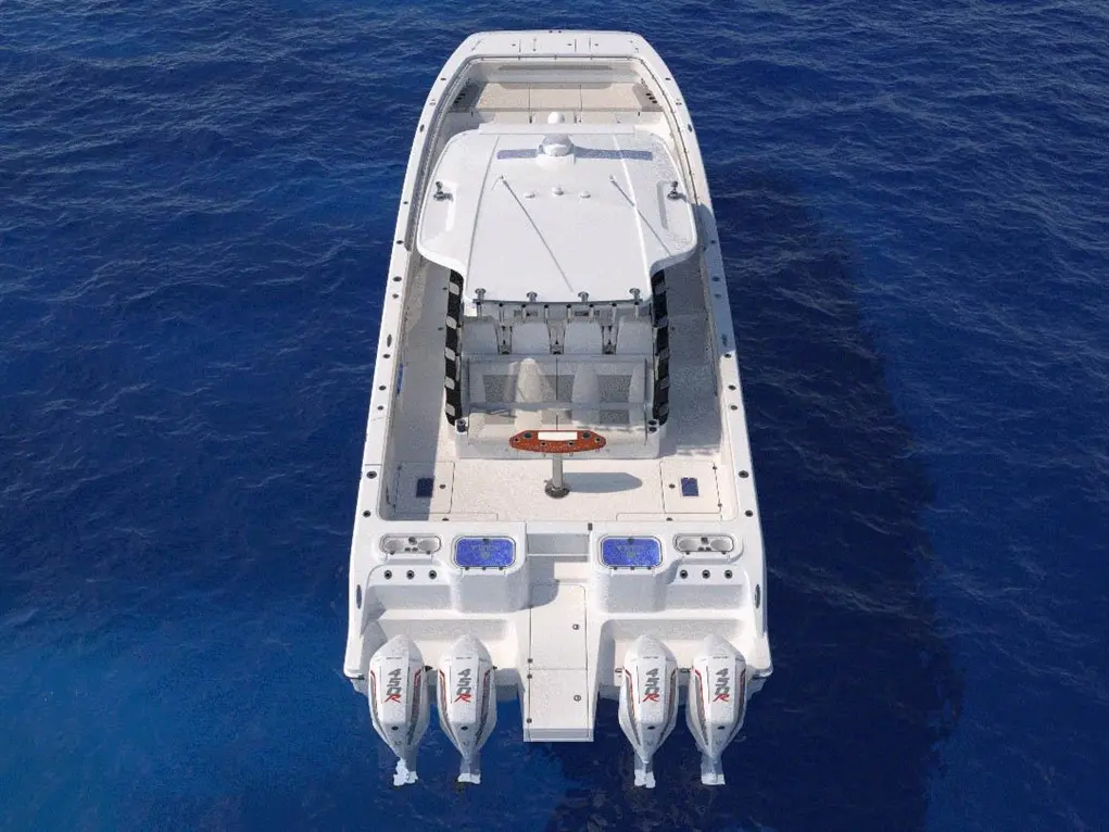 A top view of a motorboat with four outboard engines on a deep blue sea, showcasing the boat's sleek design and features.